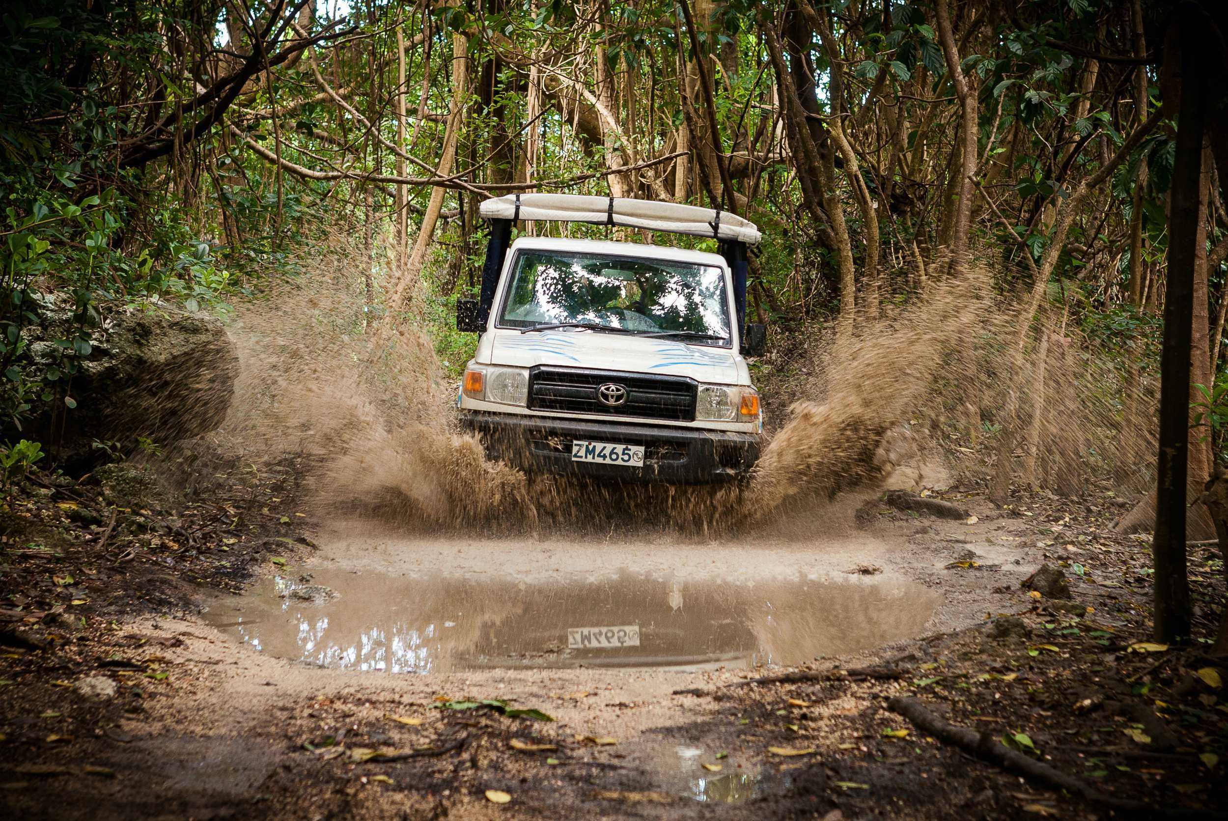 4x4 truck blasting through jungle mud crossing Caribbean